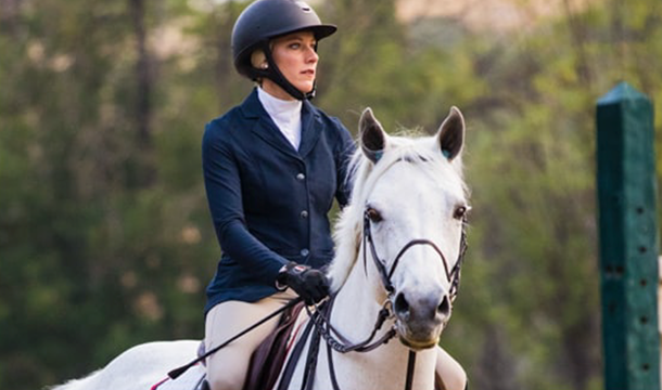 white horse with female rider in riding gear