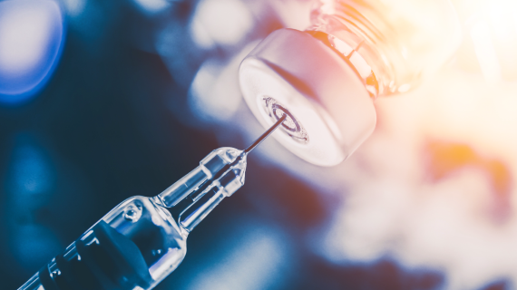 close up of syringe needle and vaccine vial