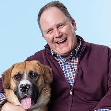 Picture of Dr. Sailor smiling while hugging a light brown dog