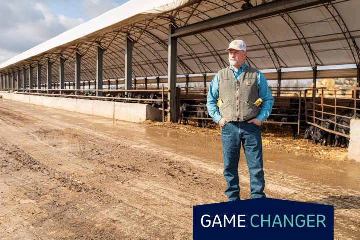Farmer standing in front of a large open-sided livestock barn